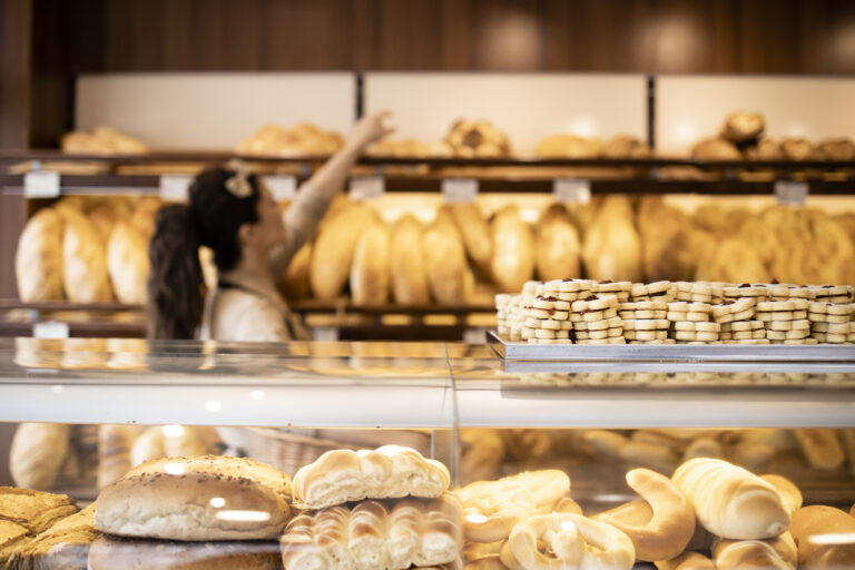 Close up view of tasty and delicious cookies in bakery shop and worker arranging pastry in background.